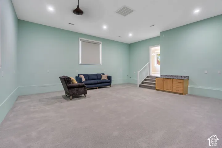 Recessed ceiling lighting illuminates a spacious room featuring wall-to-wall carpeting and a built-in wood-finish cabinet with a stone-finish countertop