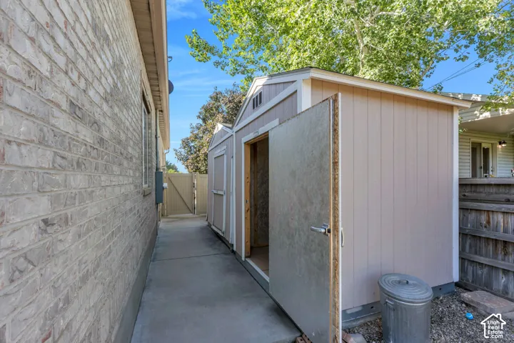 Brick exterior with a concrete pathway and two storage sheds