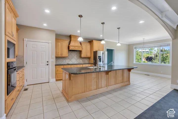 Kitchen with light wood cabinetry, granite countertops, tile flooring, and recessed lighting