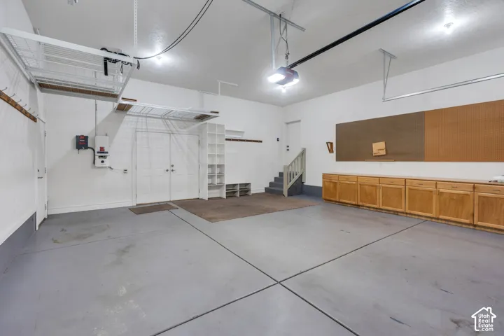 Overhead storage racks, wood-finish cabinetry, built-in shelving, two sets of double doors, and a staircase with a handrail