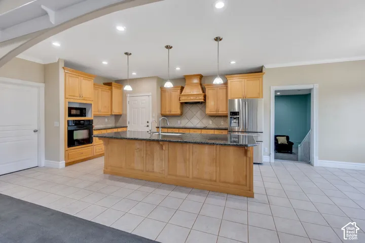 Kitchen featuring wood cabinetry, integrated stainless steel appliances, a center island with pendant lighting, and tile flooring