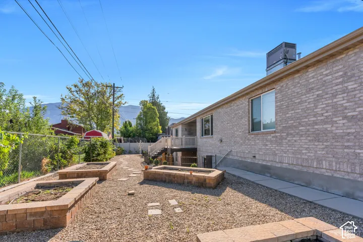Brick exterior with a ground-level patio, multiple terraced planters, and a raised deck with stairs