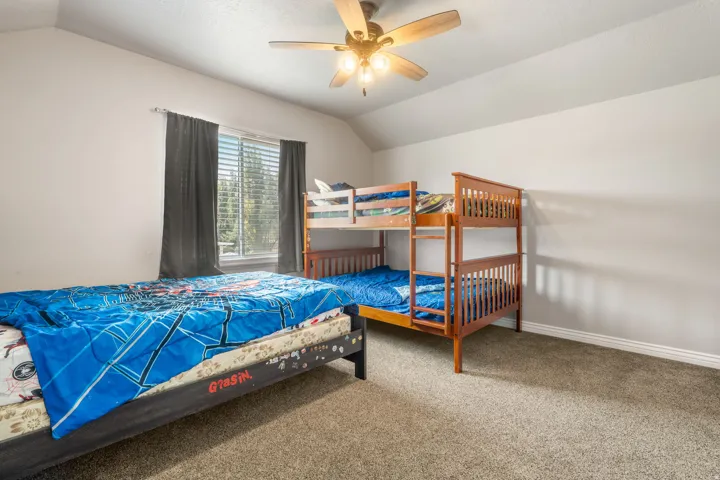 Carpeted room featuring a ceiling fan, window with blinds, and white walls