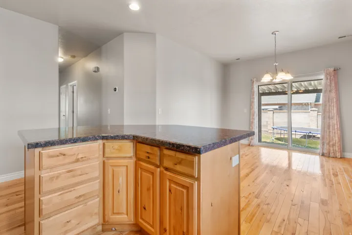 Kitchen island with wood cabinetry, dark-toned countertop, and recessed lighting