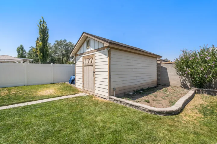 Detached shed with horizontal siding, a gabled roof, and a wood-panel door