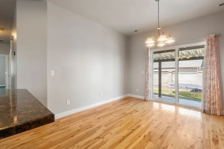 Wood-finish flooring, sliding glass door, overhead lighting fixture, and a built-in counter surface with a dark, polished finish
