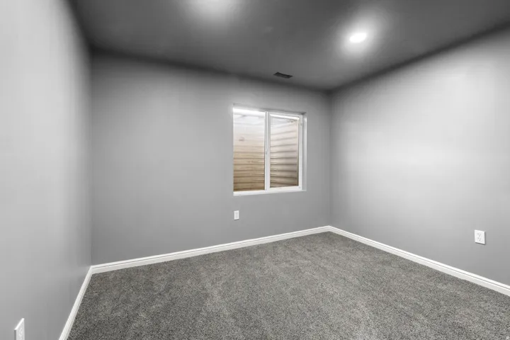 Gray wall paint, gray carpeting, white trim, recessed lighting, and a window with a light well