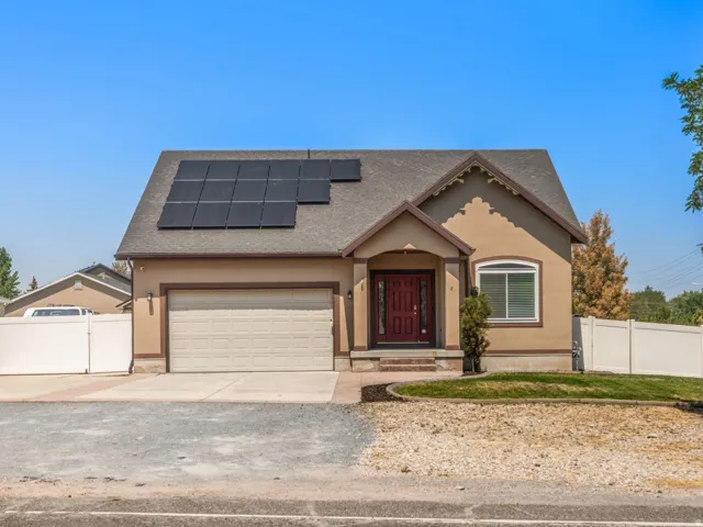 Single-story residence featuring a two-car garage, solar panels, and a red entry door