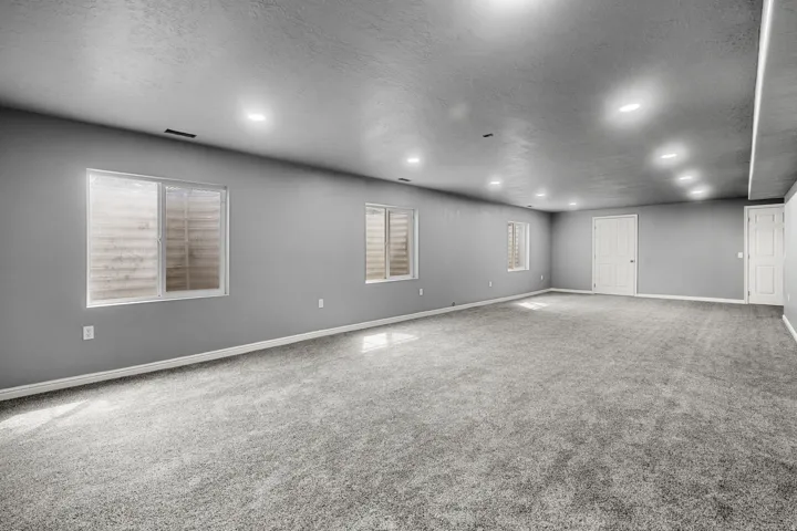Expansive carpeted area with recessed lighting, multiple windows, and white interior doors