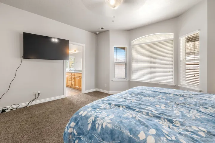 Neutral wall colors, carpeted flooring, and a ceiling fan with integrated lighting
