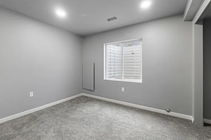 Recessed lighting, wall-to-wall carpeting, and a window with a window well