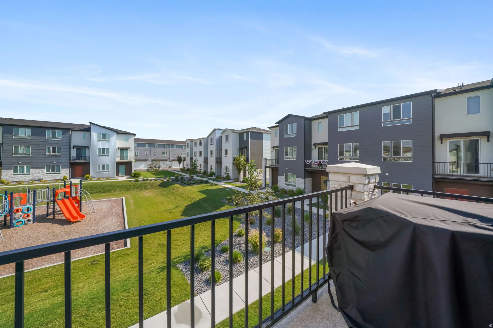 Balcony with wrought iron railing, concrete flooring, and stone pillar
