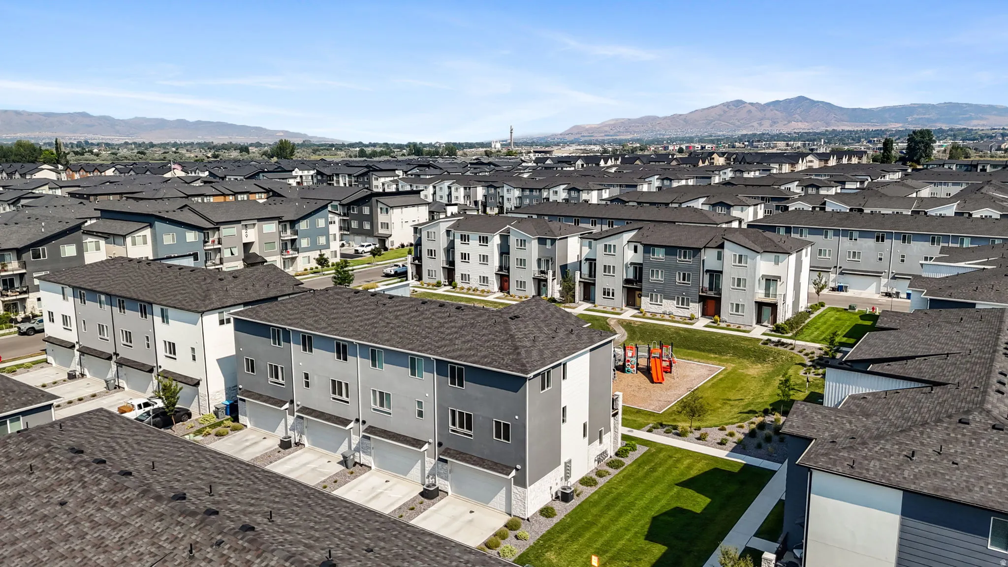 Modern townhome community featuring multi-level residences, attached garages, and a communal green space with play equipment