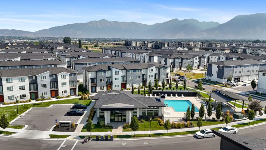 Community with mountain backdrop, central clubhouse, outdoor swimming pool, and dedicated parking