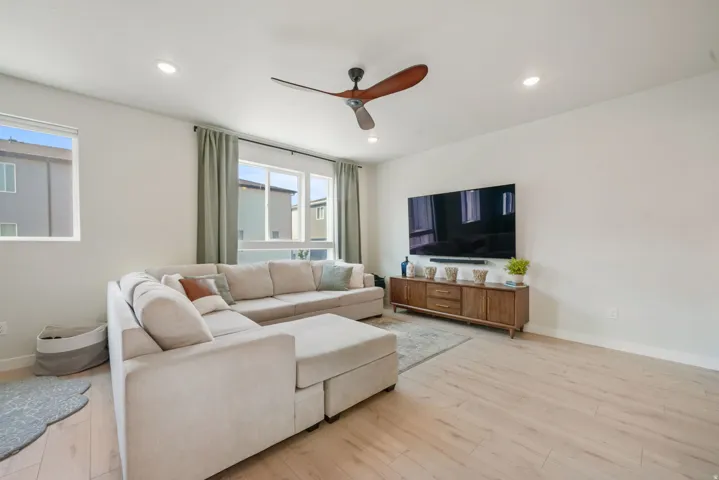 Recessed lighting, light wood-finish flooring, and multiple windows with drapery