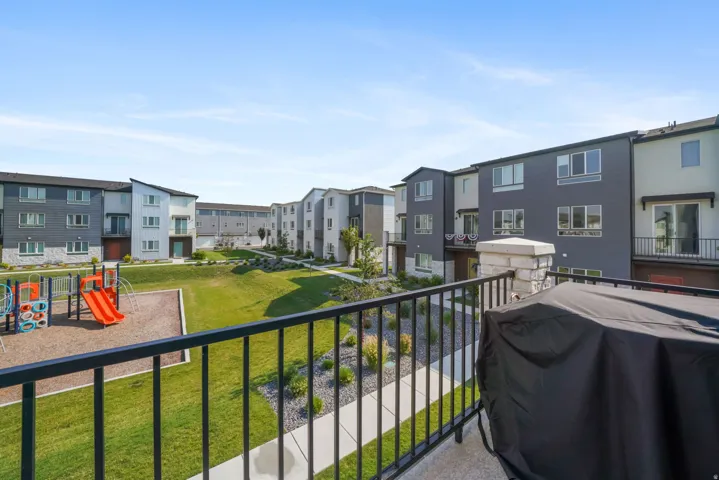 Balcony with wrought iron railing, concrete flooring, and stone pillar