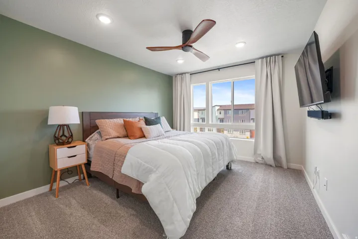 Recessed lighting, ceiling fan, large windows, wall-mounted television, and carpet flooring