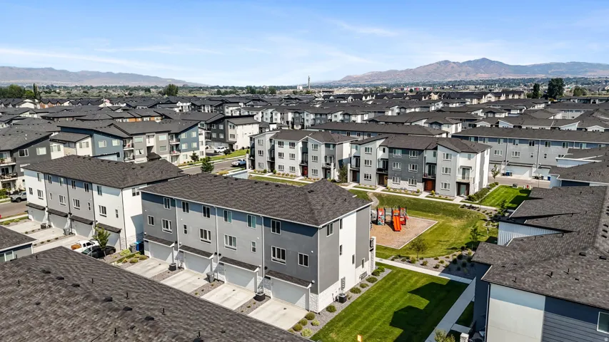 Modern townhome community featuring multi-level residences, attached garages, and a communal green space with play equipment