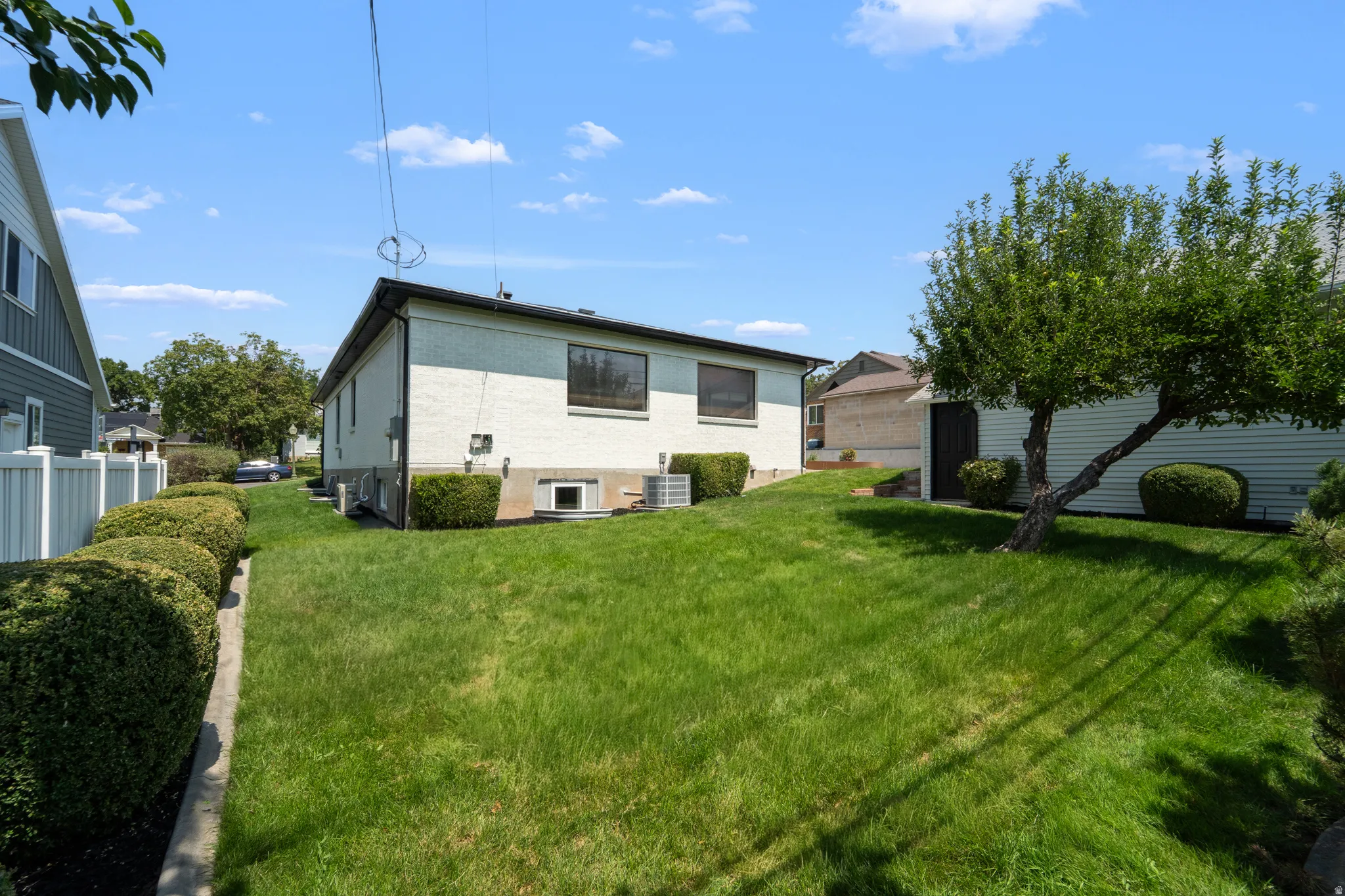 Expansive green lawn with mature trees and established perimeter shrubs
