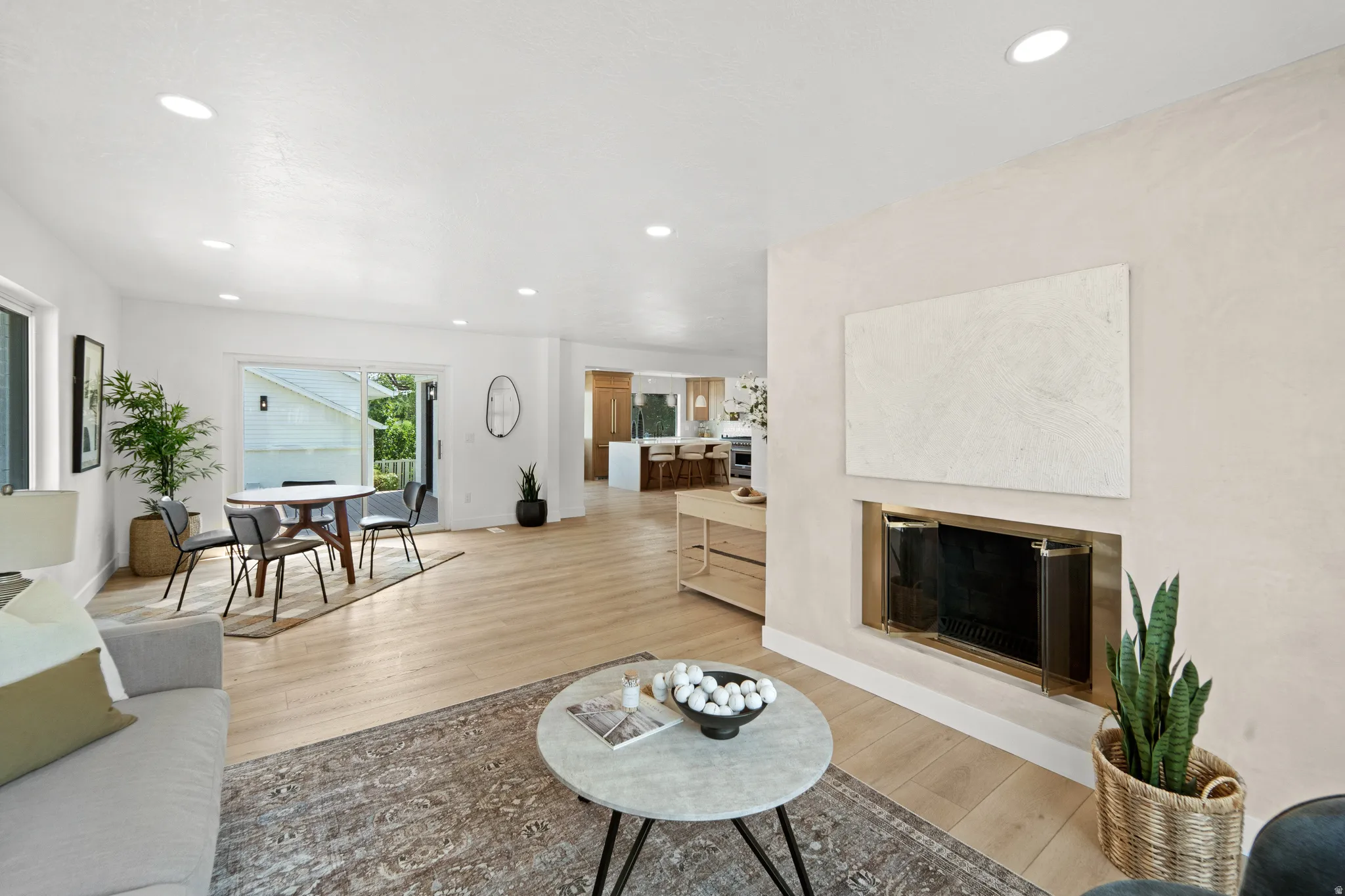 Recessed lighting illuminates the open-concept living space, featuring wood-finish flooring and a built-in fireplace
