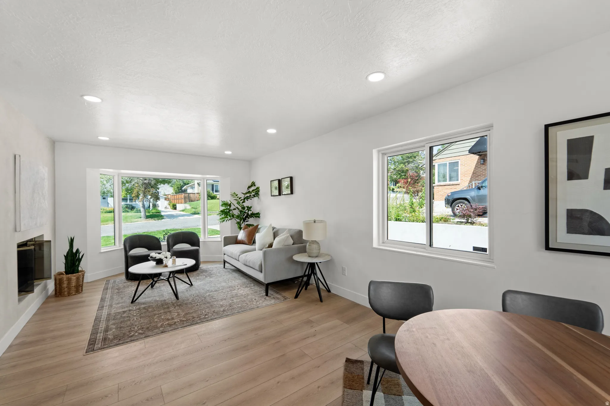 Recessed lighting, wood-finish flooring, a built-in fireplace, and expansive windows create a bright and inviting interior