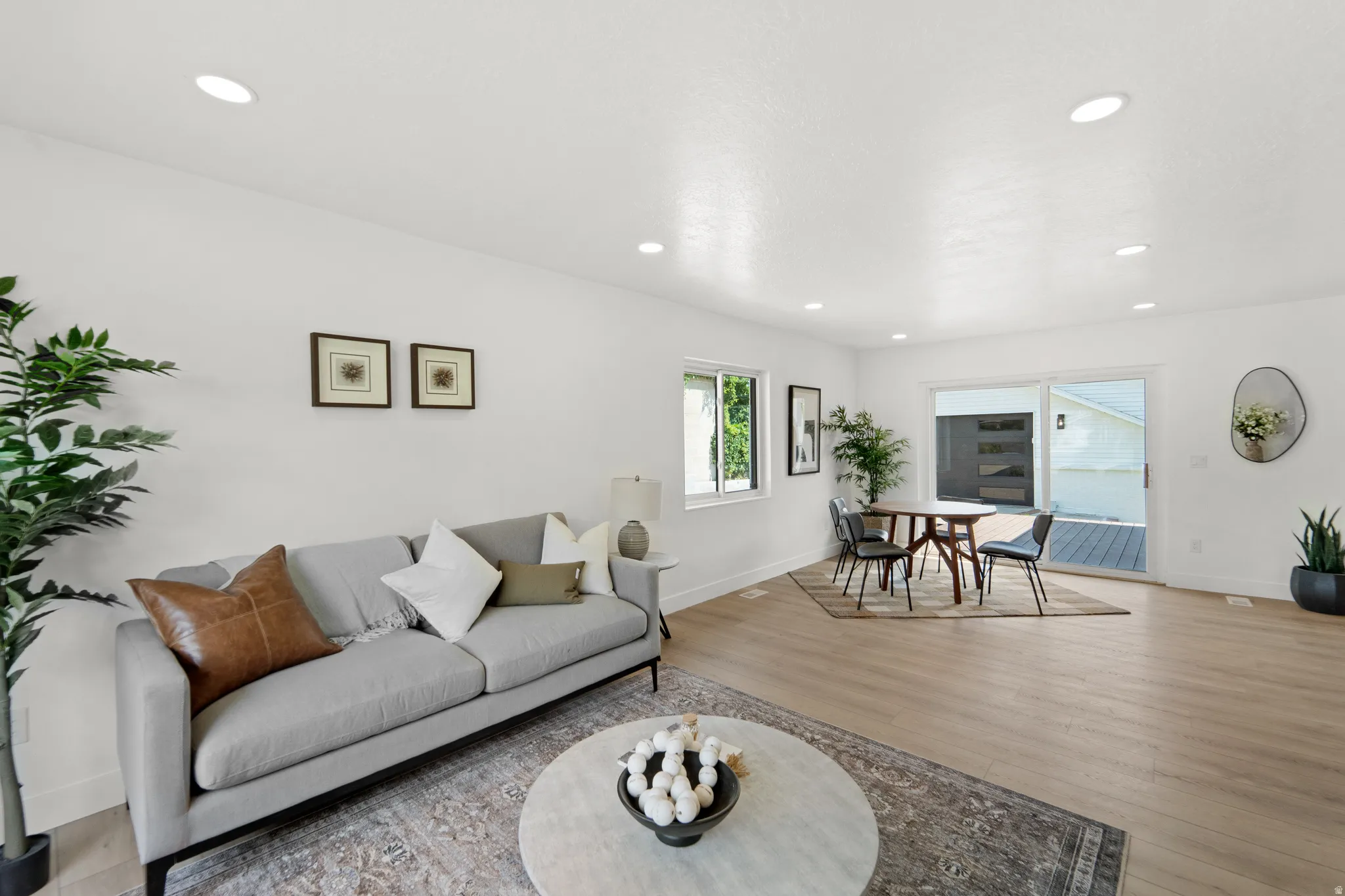 Recessed lighting illuminates an open living area featuring light wood-finish flooring