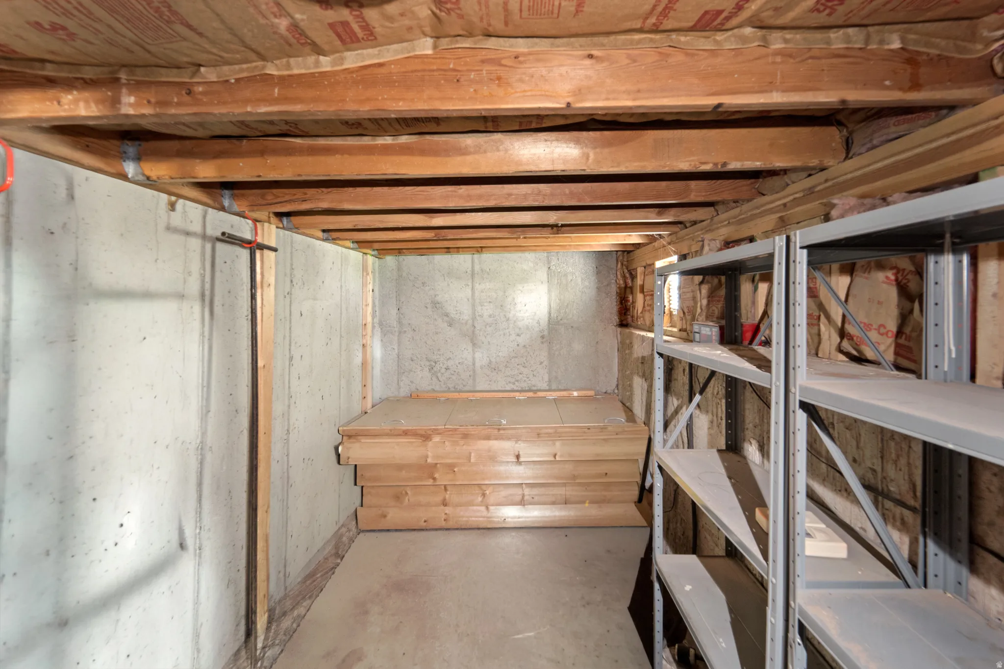 Concrete wall construction, exposed wood joists, steel shelving, and wood-finish flooring