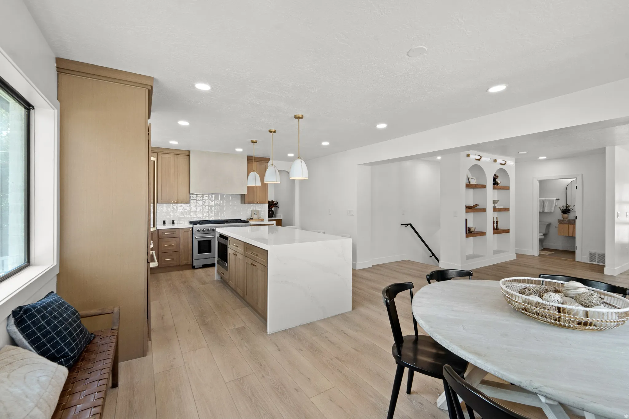 Kitchen featuring recessed lighting, a large island with a waterfall countertop, and wood-finish flooring