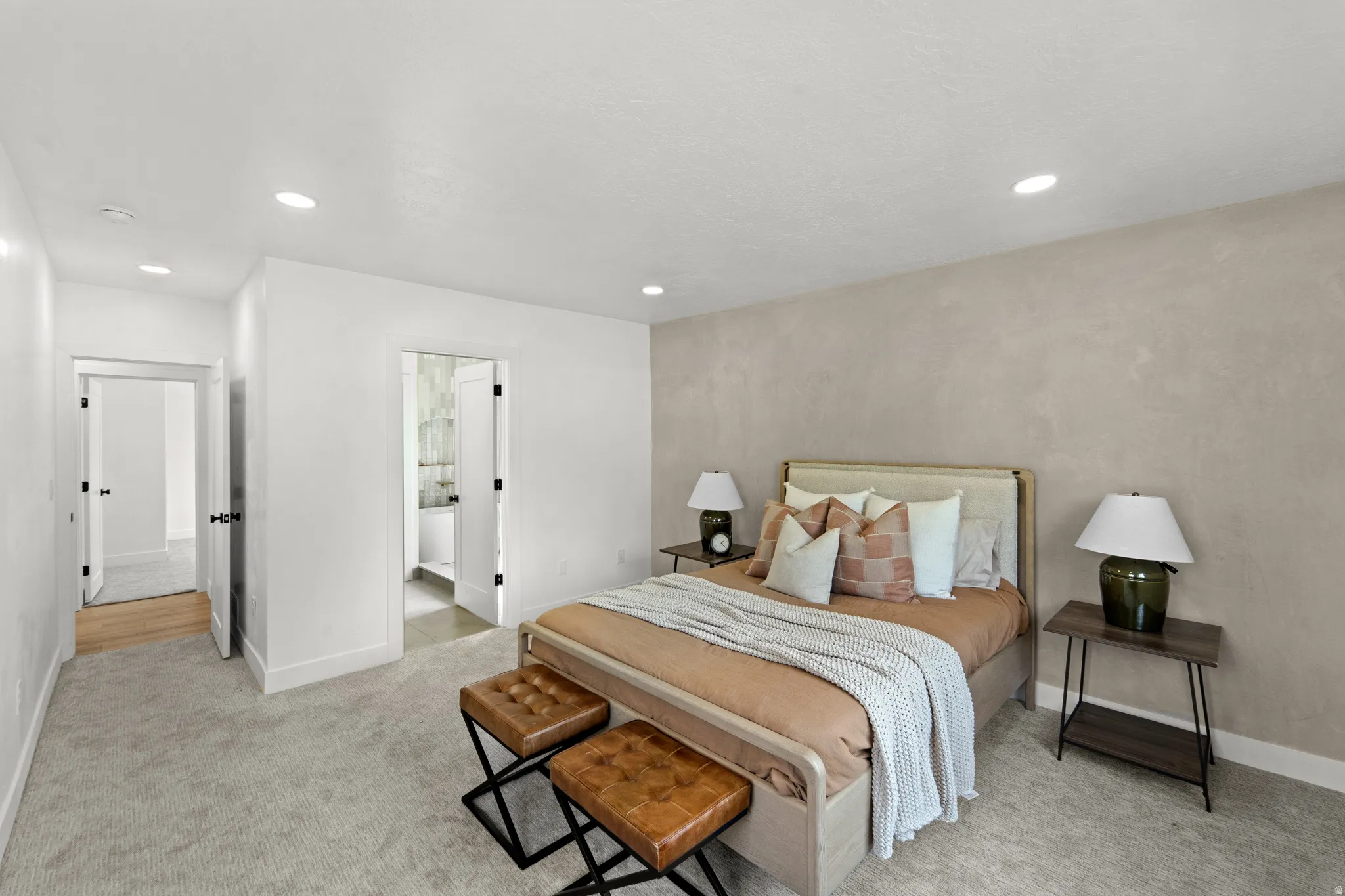 Recessed lighting, light-toned carpeting, neutral wall finishes, and a doorway to an additional room