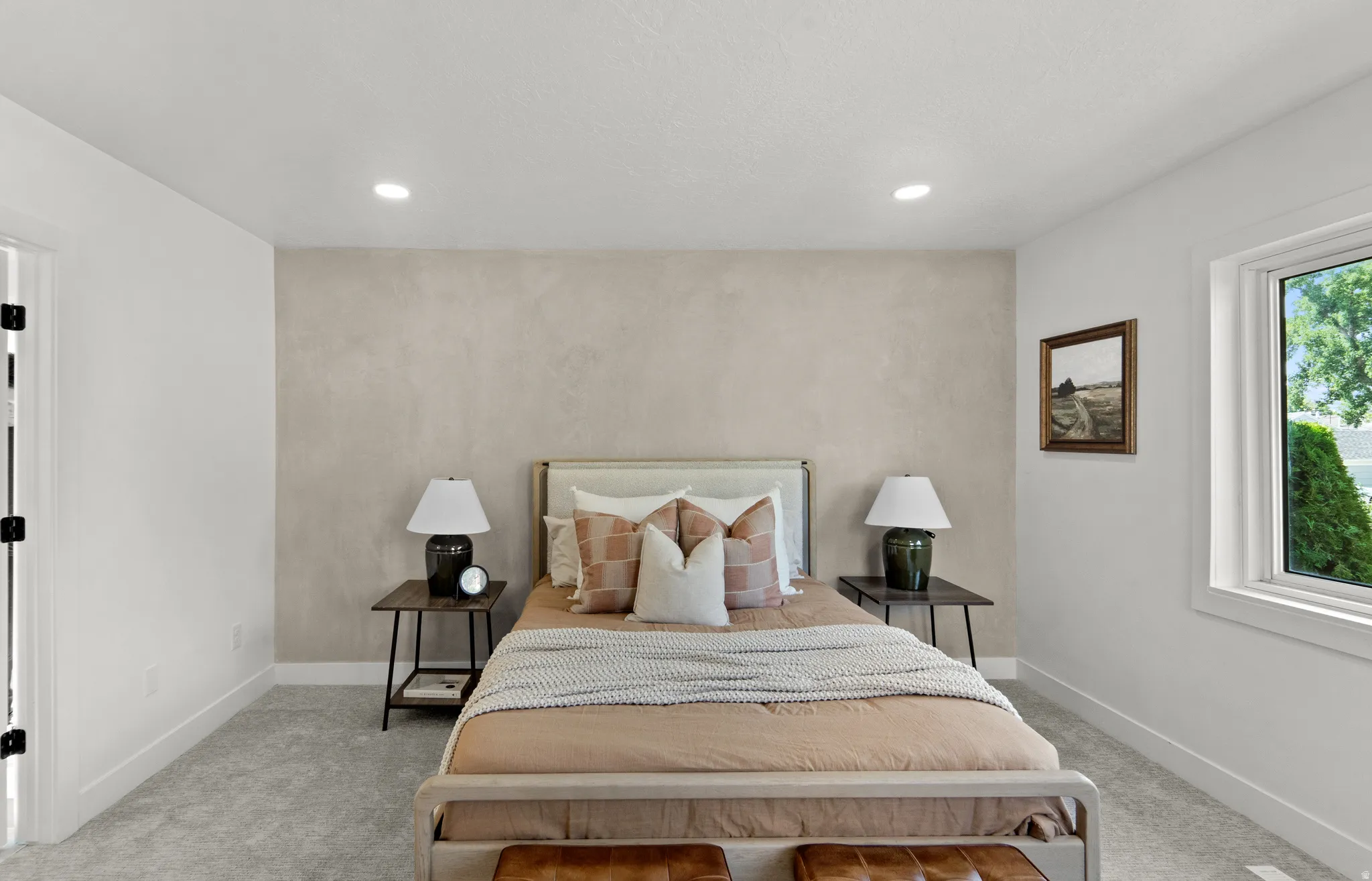 Textured accent wall, recessed lighting, double-paned window, neutral carpeting, and a wood-finish bed frame