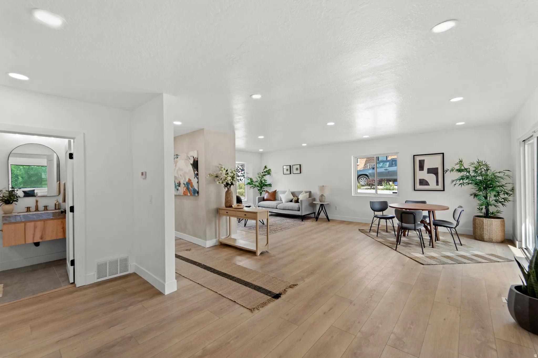 Recessed lighting throughout, wood-finish flooring, and a modern floating vanity with a vessel sink