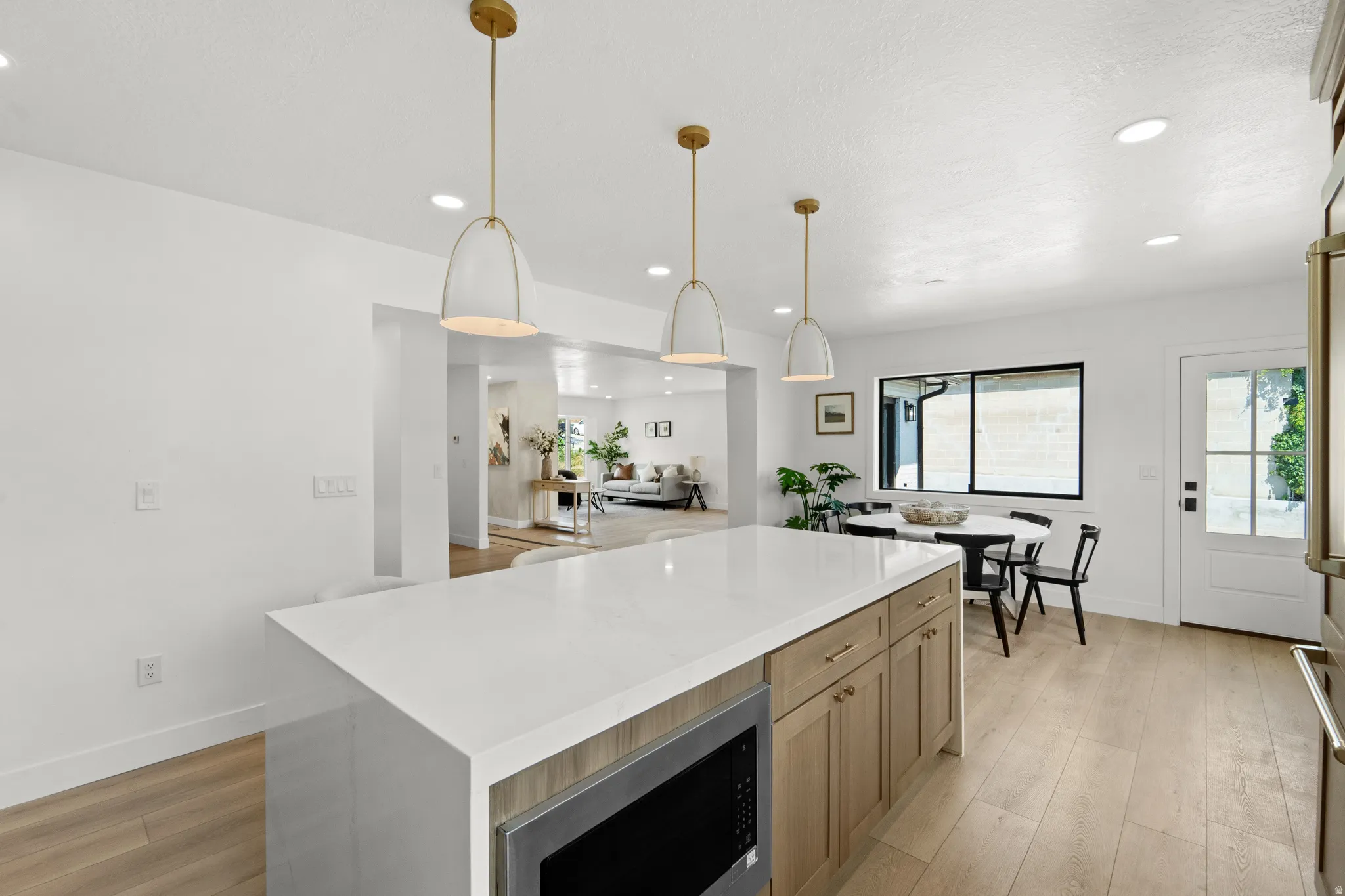 Kitchen featuring a central island with a light-toned countertop, wood-finish flooring, recessed lighting, and a white paneled door with windowpanes