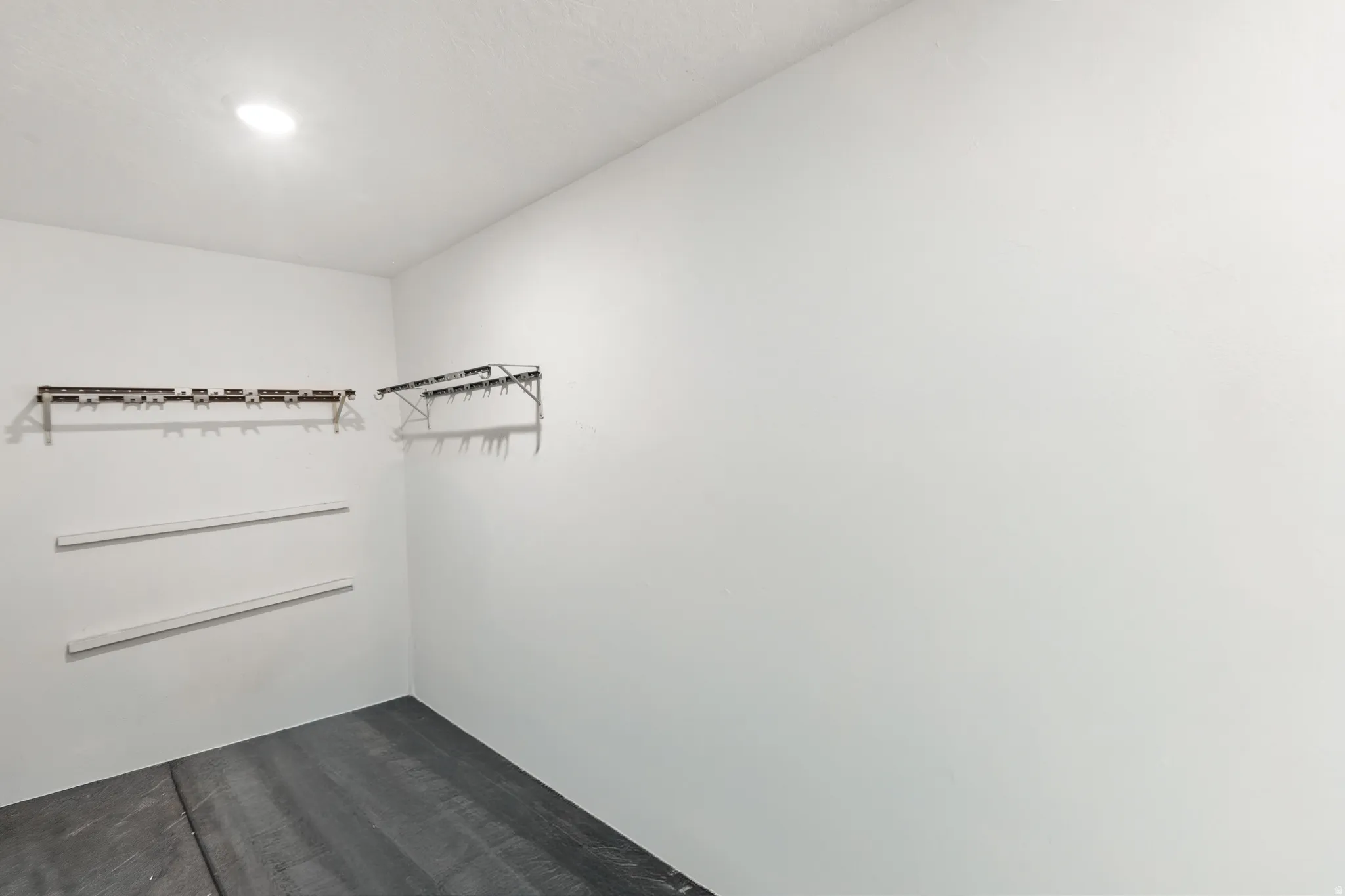 Recessed ceiling light, white painted walls, wall-mounted shelving brackets, unfinished flooring