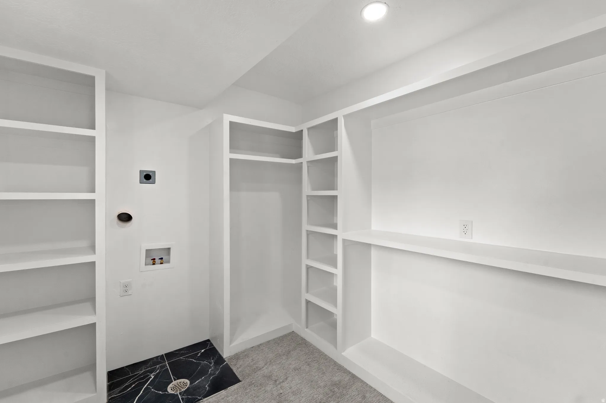 Built-in shelving, integrated closet space, recessed lighting, and a dark stone-finish floor section with drainage
