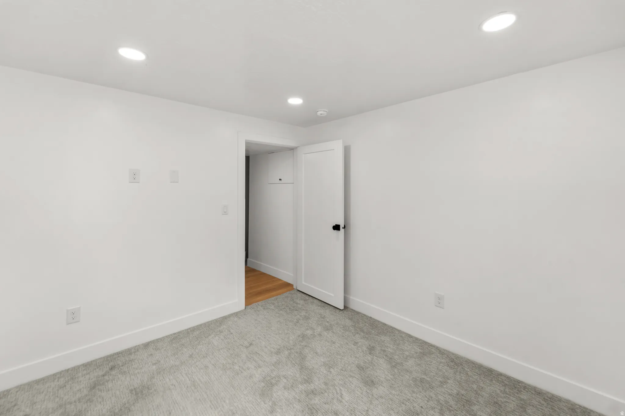 Recessed lighting, light gray carpeting, white walls, and white trim