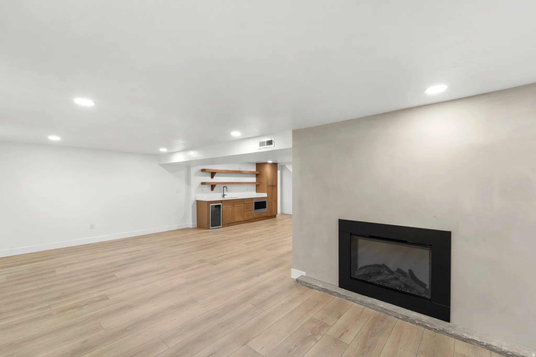 Built-in electric fireplace, recessed lighting, wood-finish flooring, built-in wet bar with shelving, integrated beverage cooler