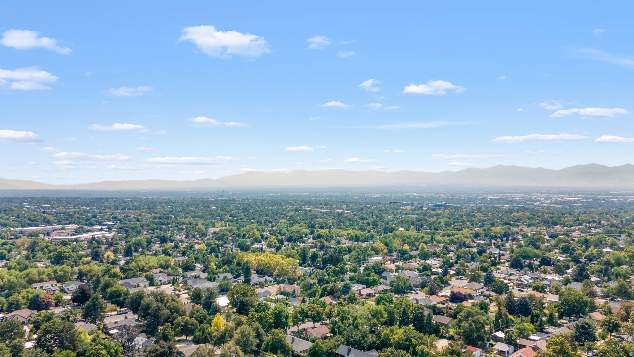 Expansive aerial perspective showcasing a residential neighborhood under a clear sky with distant mountain ranges