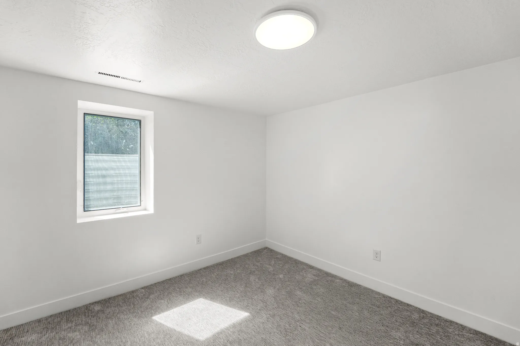 Bright, finished room featuring neutral wall finishes, recessed ceiling lighting, carpet flooring, and a large window with natural light exposure
