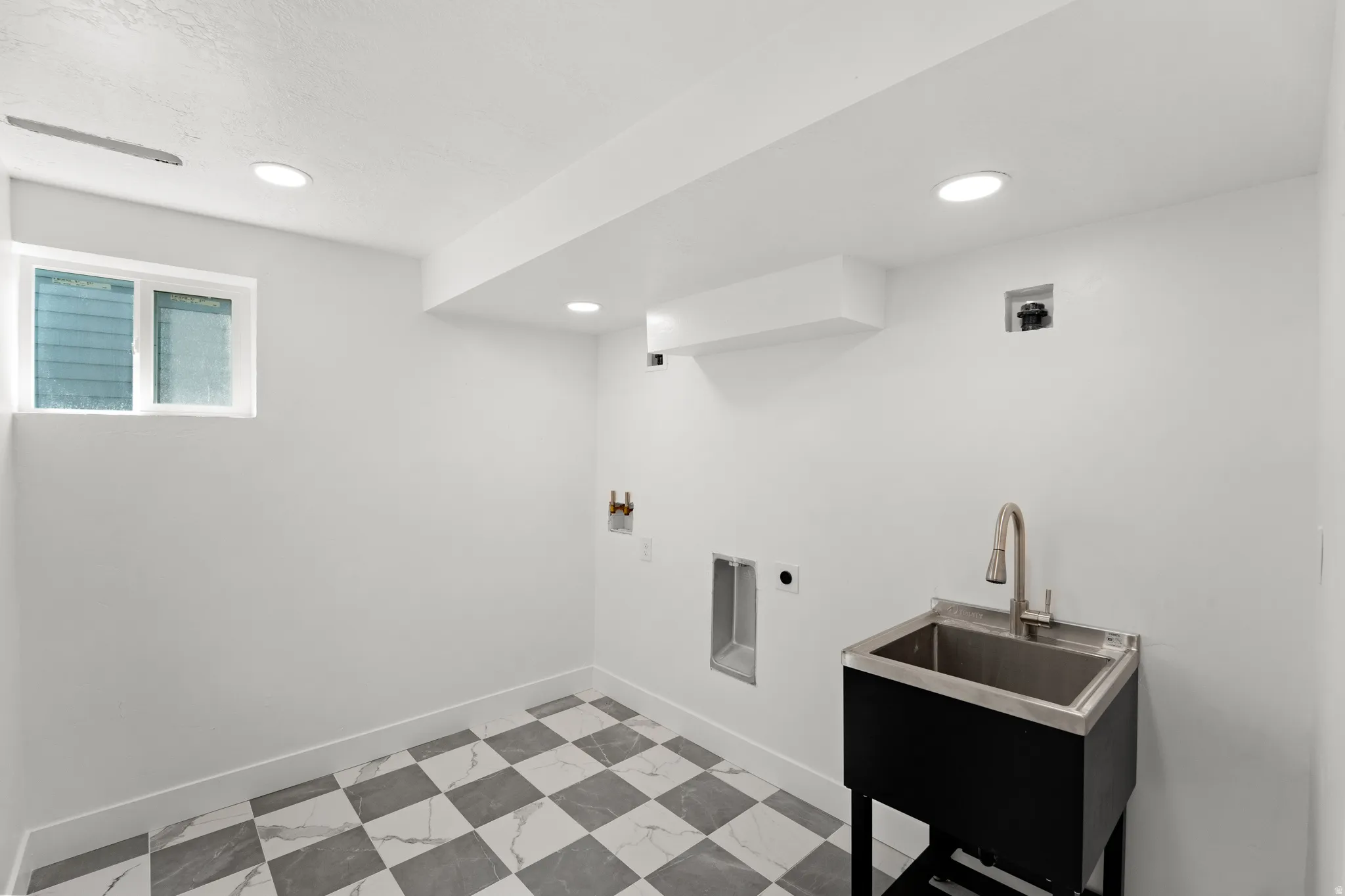Utility sink with stainless steel basin, checkered tile flooring, recessed lighting, and a window