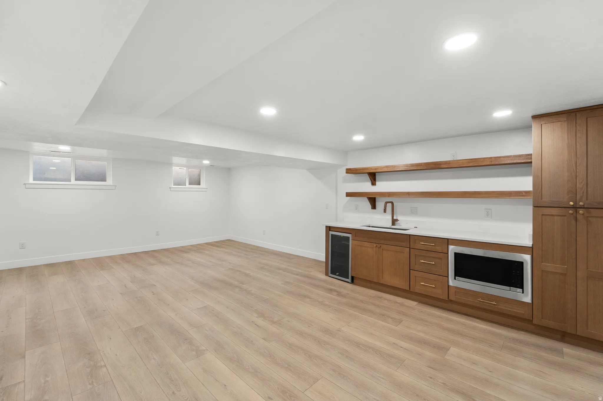 Spacious room featuring wood-finish flooring, recessed lighting, and white walls