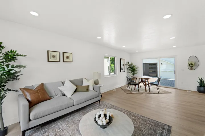 Recessed lighting illuminates an open living area featuring light wood-finish flooring