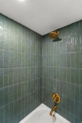 Porcelain bathtub with teal tile surround and brass fixtures