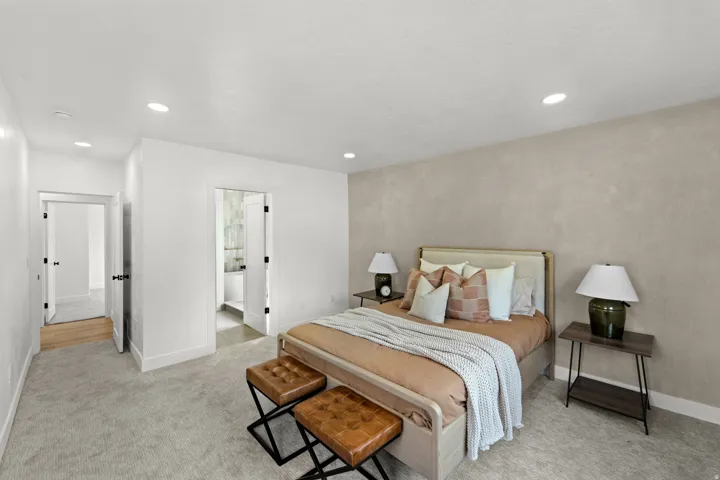 Recessed lighting, light-toned carpeting, neutral wall finishes, and a doorway to an additional room