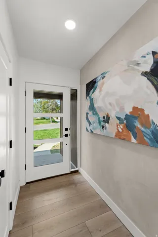 Bright entryway featuring recessed ceiling lighting, wide-plank wood-finish flooring, and clean white trim throughout