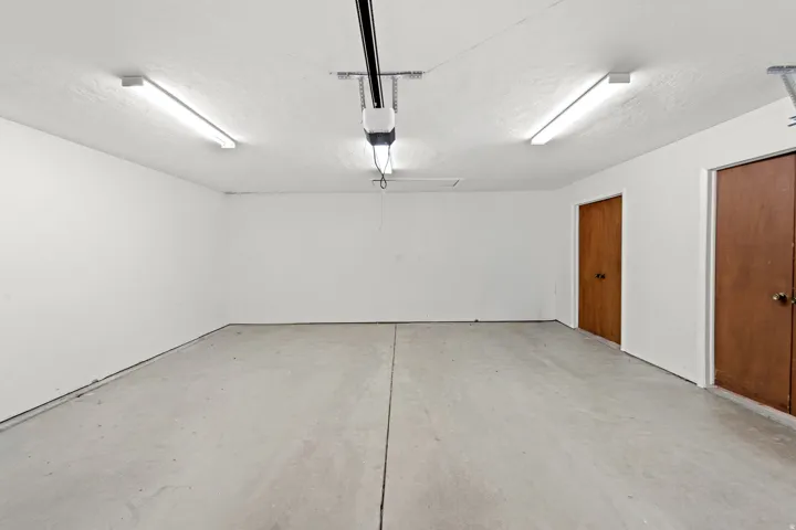 Concrete flooring, white painted walls, two flush-mount ceiling lights, and two wood-finish doors