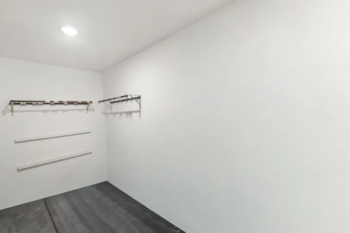 Recessed ceiling light, white painted walls, wall-mounted shelving brackets, unfinished flooring