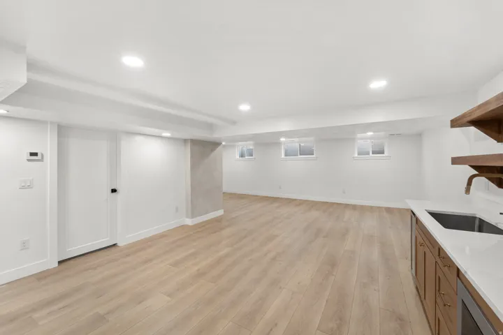 Recessed lighting illuminates the wood-finish flooring, complemented by multiple windows