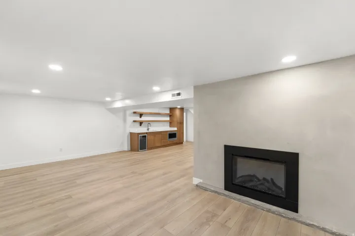 Built-in electric fireplace, recessed lighting, wood-finish flooring, built-in wet bar with shelving, integrated beverage cooler