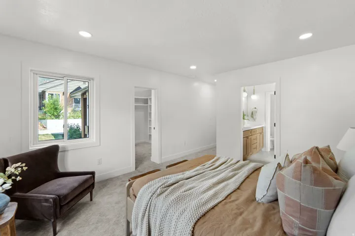 Recessed ceiling lighting, white walls, carpeted flooring, and a window with white trim