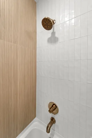 Tub and shower combination featuring a bronze-finish shower head and faucet set